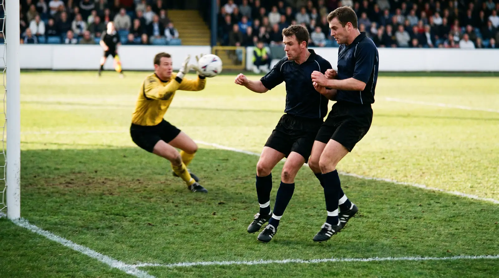 Premier League defenders clearing a high cross inside the penalty area during a top-flight match