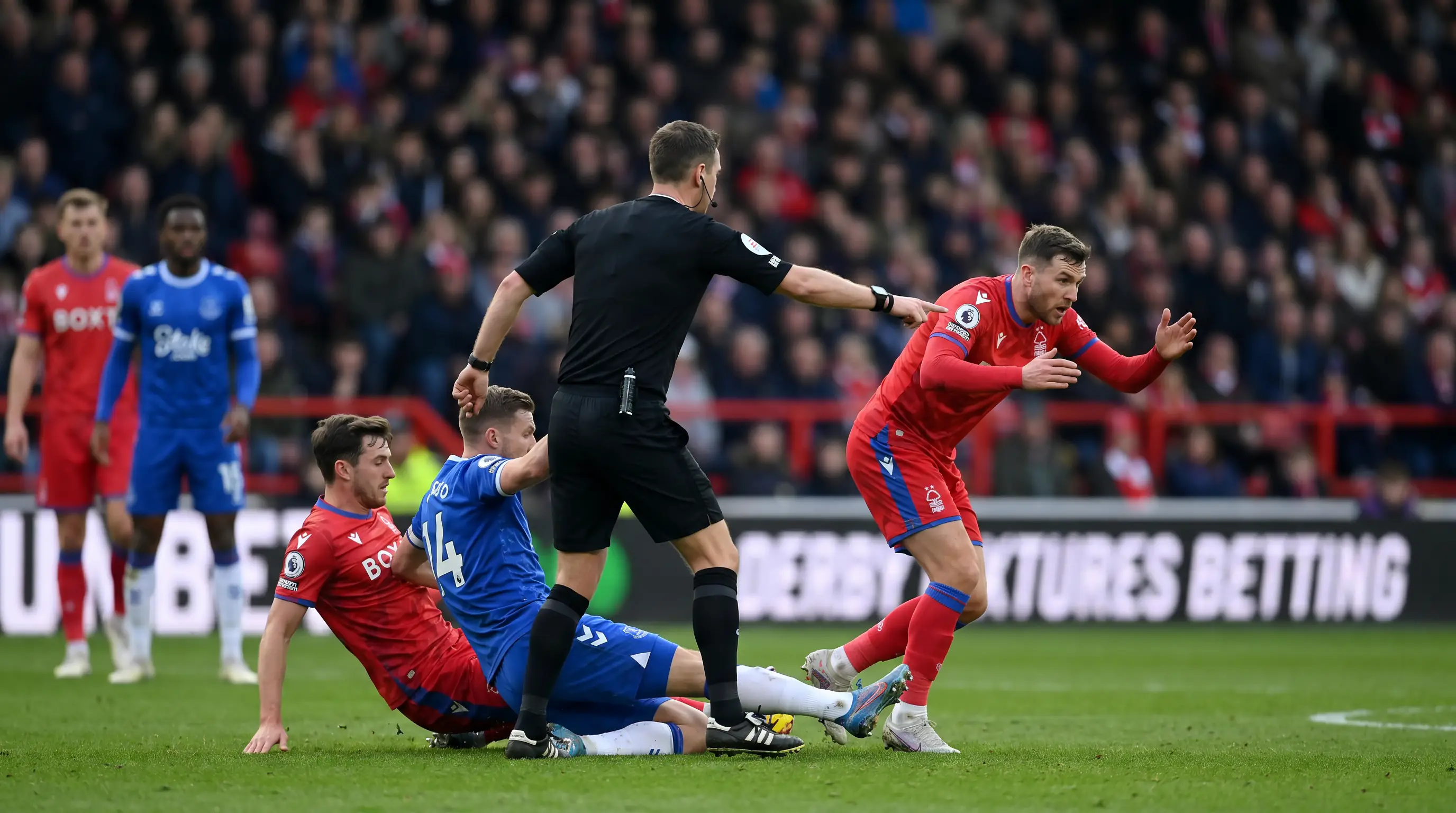 Hard tackle and confrontation in a derby fixture as the referee intervenes
