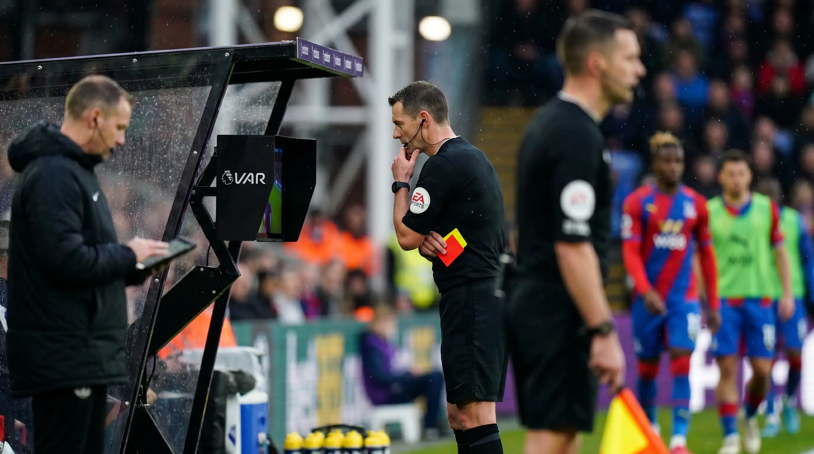 Referee consulting the VAR monitor during a Premier League match for a card decision